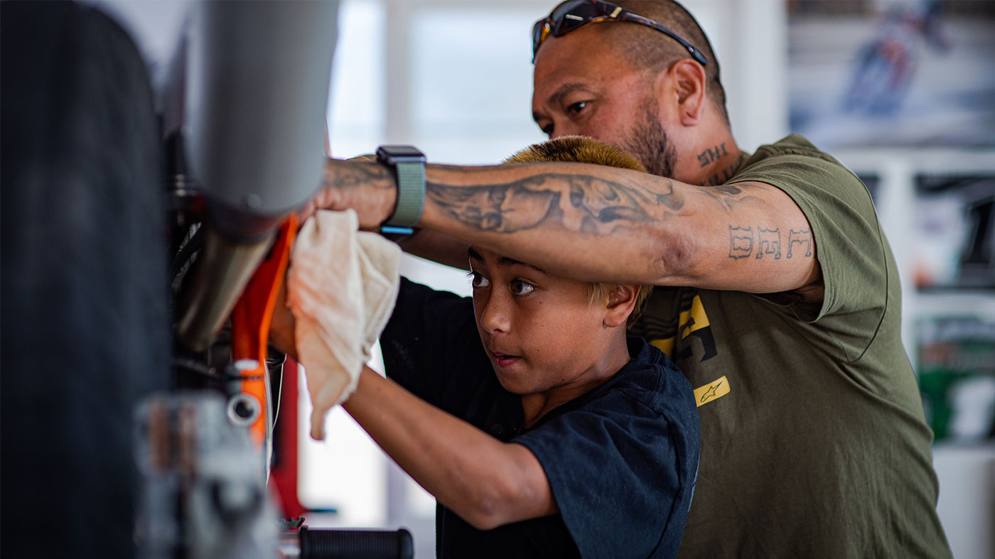 Kage and his father working on a motorcycle in a garage.